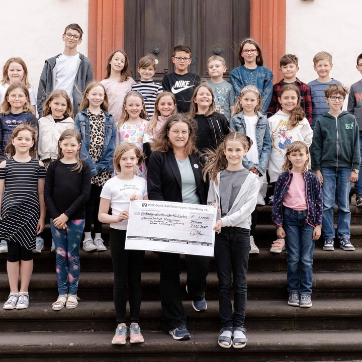 Gruppenfoto: Kommunionkinder aus Zellingen und Retzbach überreichen symbolisch einen Spendenscheck