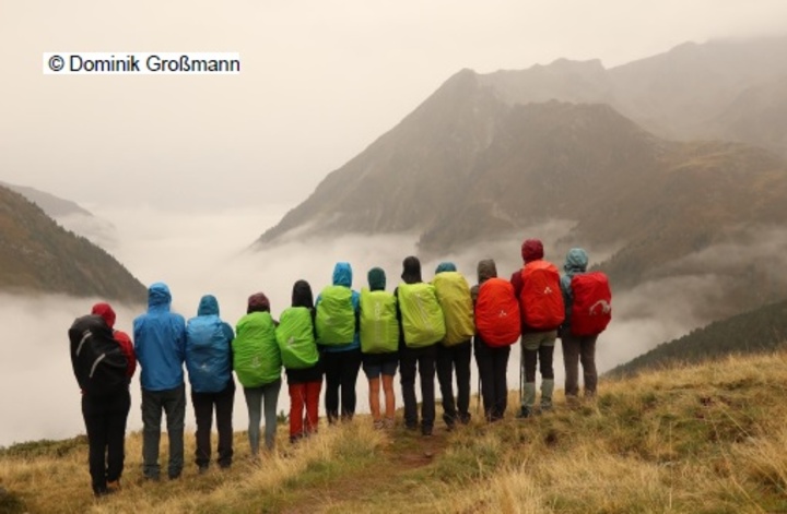 Bergsteiger im Nebel mit regenbogen-farbenen Rucksäcken